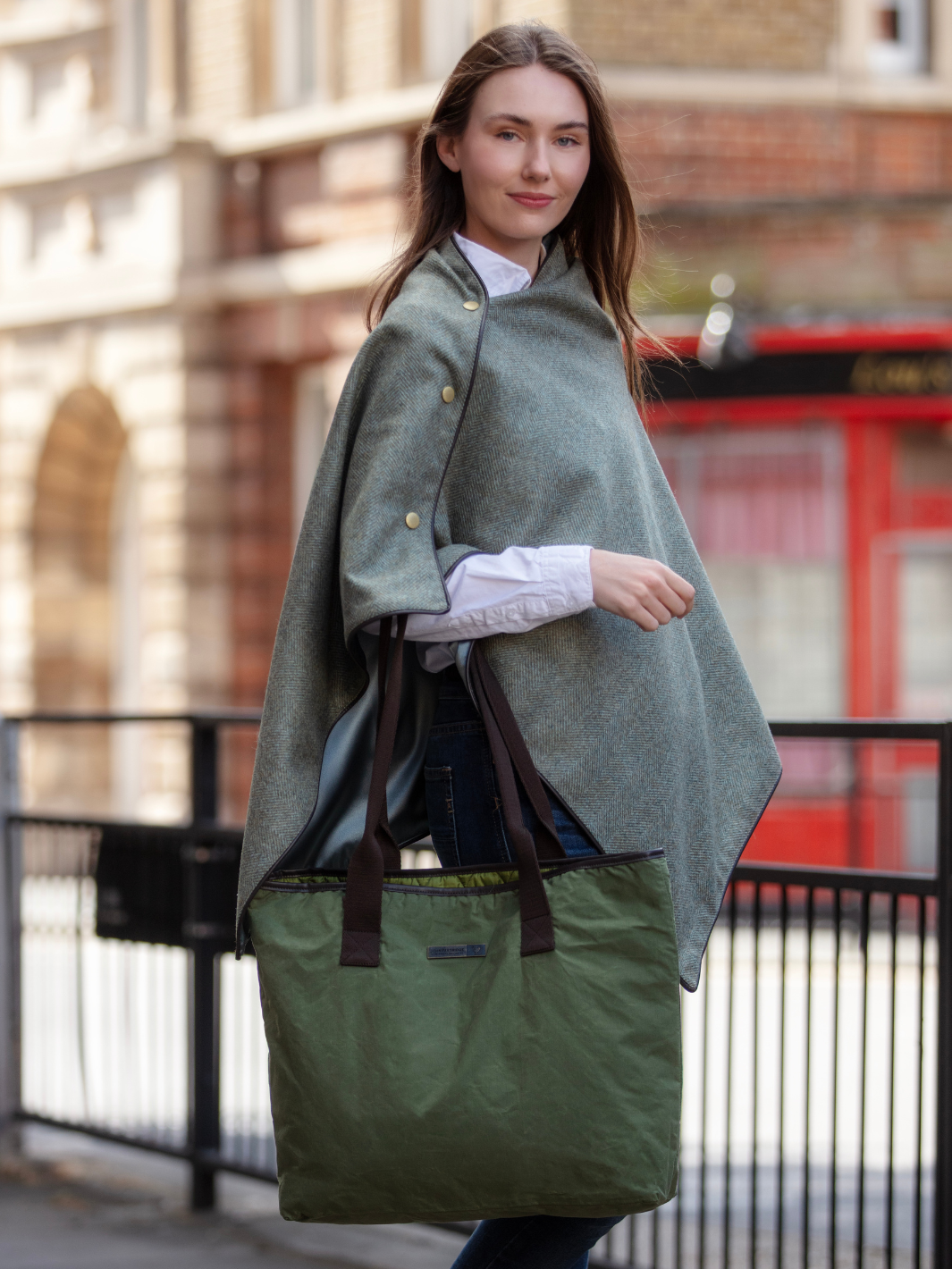 Green herringbone tweed shawl with burgundy satin lining, gold studs, and dark brown faux leather trim, made in the UK by John Partridge.