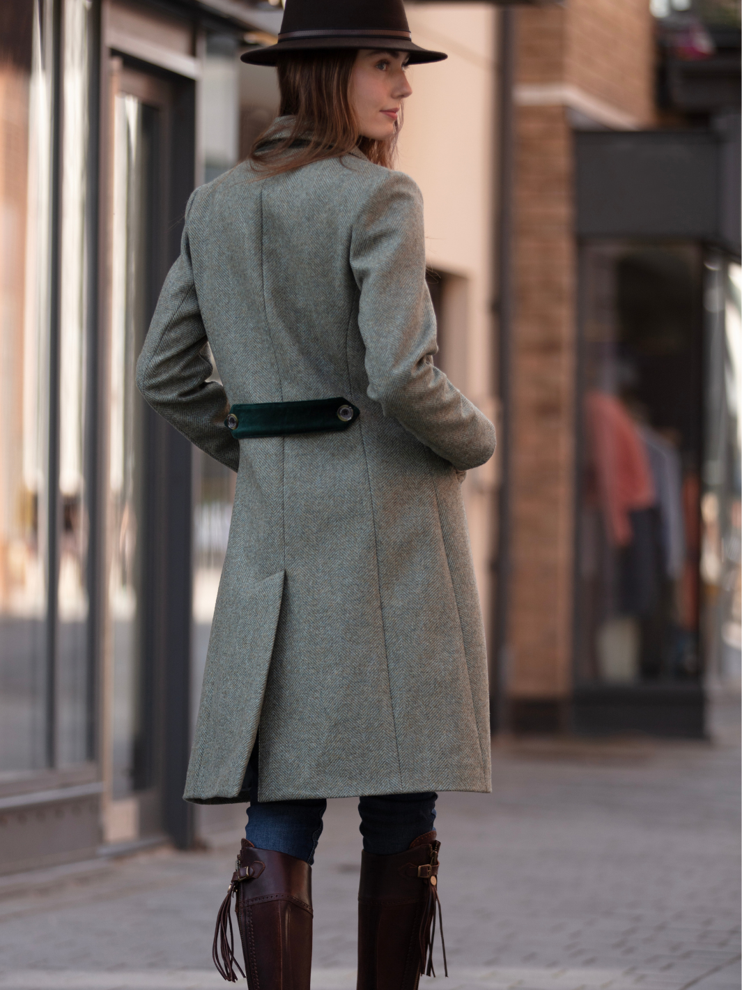 Lichfield Long Ladies' Tweed Coat in pastel green herringbone wool with John Partridge branded buttons, soft satin turquoise lining, forest green velvet cuffs and under collar, and reversible back belt. Features include 2 front pockets, back vent, and knee-length design. Available in pastel green, pink, and blue. Made in England.