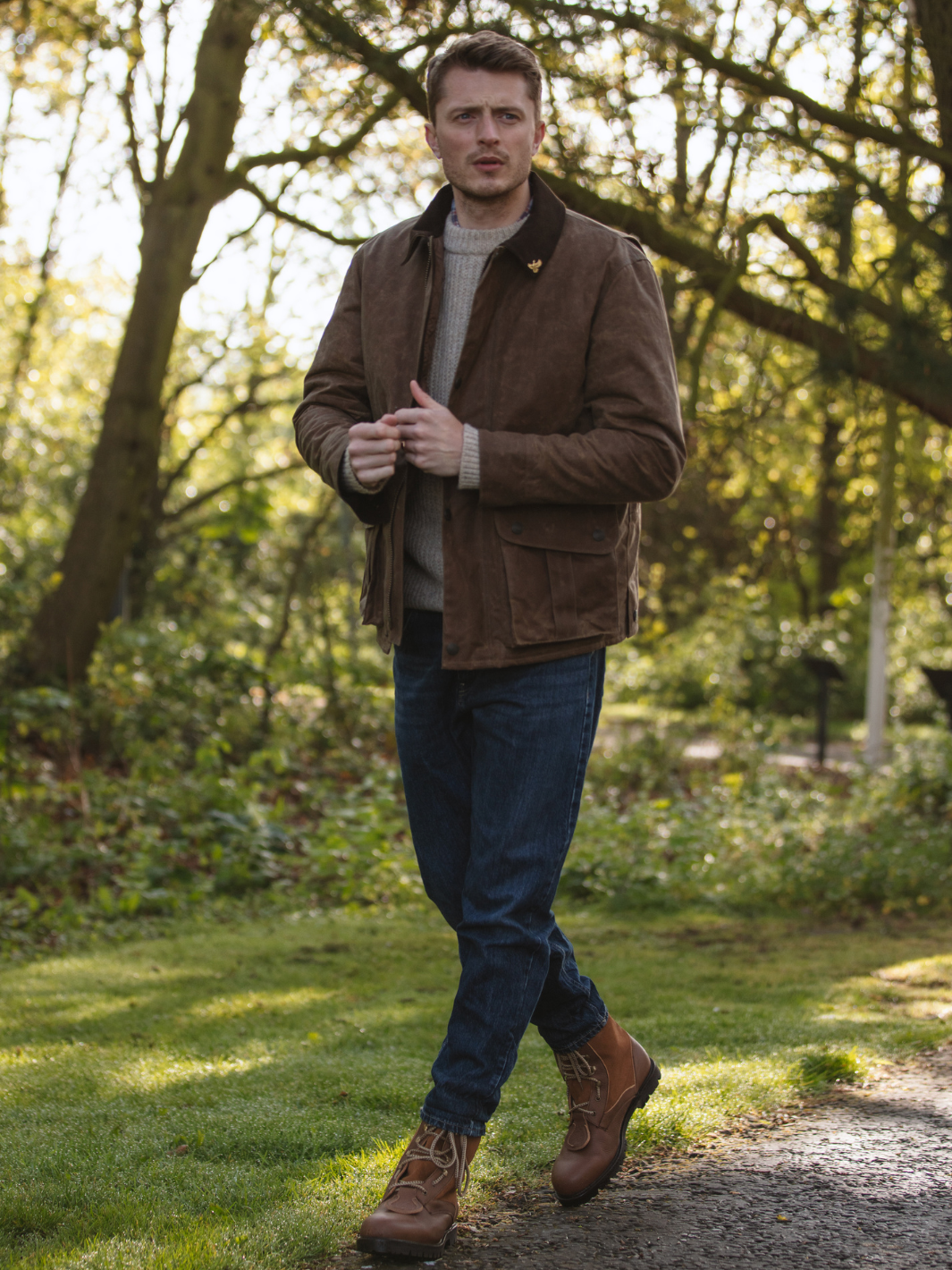 Hinterland Jacket in heavy tan waxed cotton with a desert finish, featuring a hip-length design, oversized fit, quilted brown lining, dark brown moleskin trims, and antique brass plate. Includes 2 front pockets, zipped pocket, inner wallet pocket, and YKK zip with storm flap. Limited edition, part of Partridge England's range.