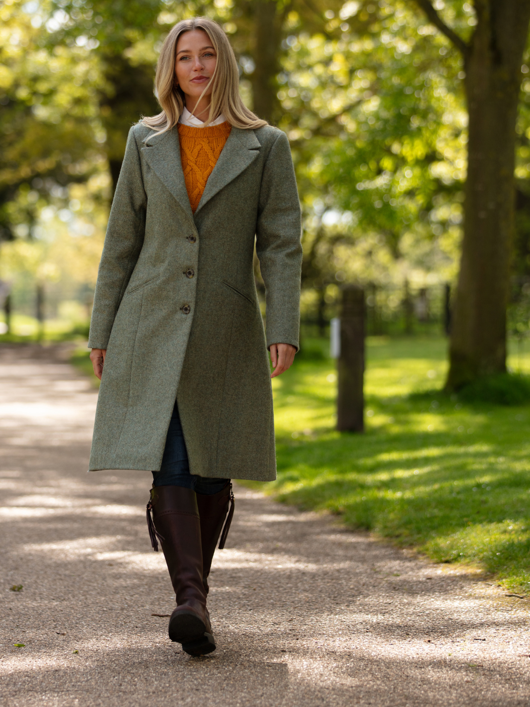 Lichfield Long Ladies' Tweed Coat in pastel green herringbone wool with John Partridge branded buttons, soft satin turquoise lining, forest green velvet cuffs and under collar, and reversible back belt. Features include 2 front pockets, back vent, and knee-length design. Available in pastel green, pink, and blue. Made in England.