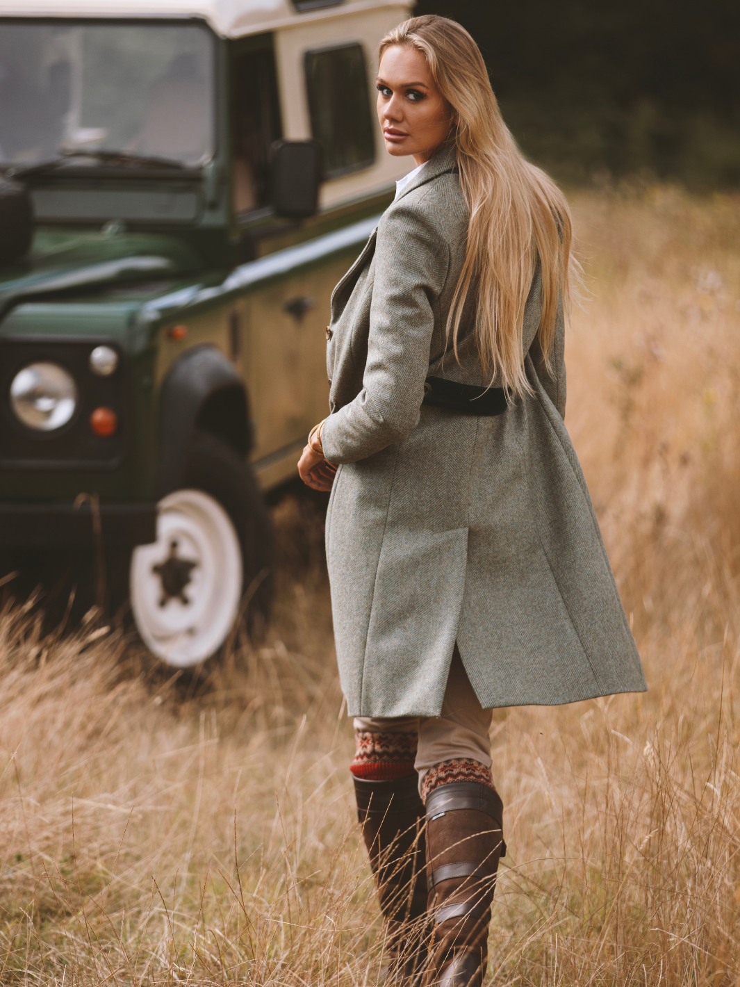 Lichfield Long Ladies' Tweed Coat in pastel green herringbone wool with John Partridge branded buttons, soft satin turquoise lining, forest green velvet cuffs and under collar, and reversible back belt. Features include 2 front pockets, back vent, and knee-length design. Available in pastel green, pink, and blue. Made in England.