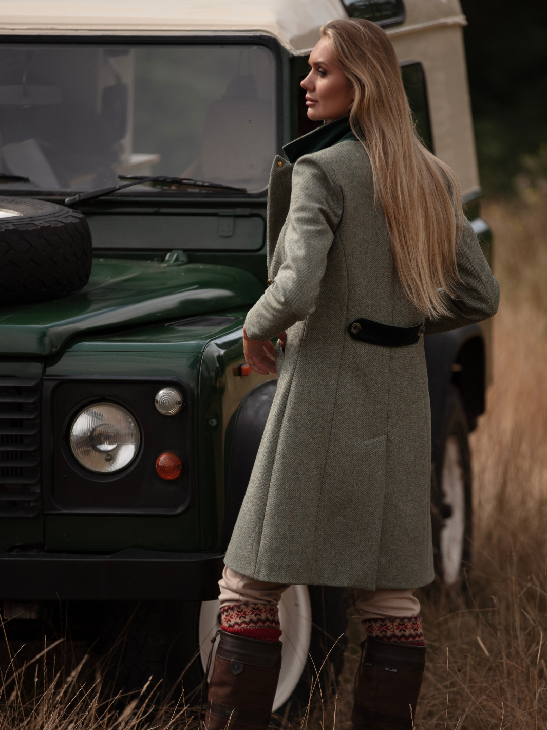 Lichfield Long Ladies' Tweed Coat in pastel green herringbone wool with John Partridge branded buttons, soft satin turquoise lining, forest green velvet cuffs and under collar, and reversible back belt. Features include 2 front pockets, back vent, and knee-length design. Available in pastel green, pink, and blue. Made in England.
