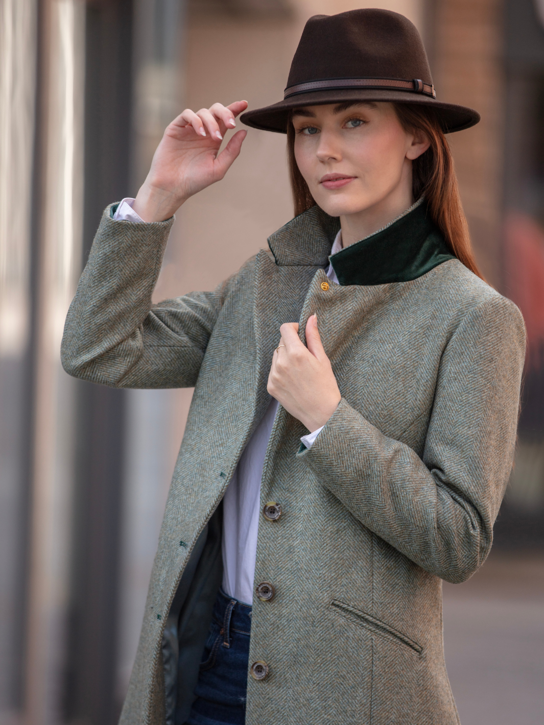 Lichfield Long Ladies' Tweed Coat in pastel green herringbone wool with John Partridge branded buttons, soft satin turquoise lining, forest green velvet cuffs and under collar, and reversible back belt. Features include 2 front pockets, back vent, and knee-length design. Available in pastel green, pink, and blue. Made in England.
