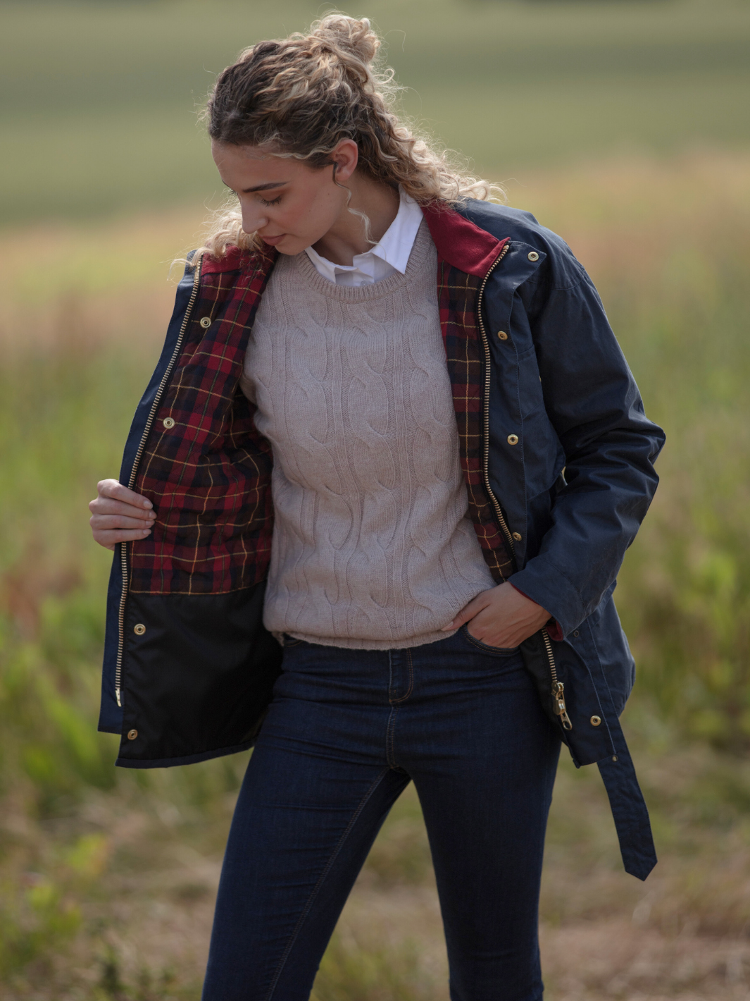 Wax Biker Jacket in Ocean Navy with cherry check lining, burgundy cotton moleskin collar, oversized pockets, and detachable belt. Crafted from British waxed material with tonal embroidery and gold-coloured studs for a blend of tradition, luxury, and modern function.