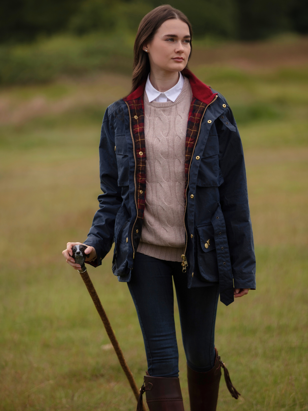 Wax Biker Jacket in Ocean Navy with cherry check lining, burgundy cotton moleskin collar, oversized pockets, and detachable belt. Crafted from British waxed material with tonal embroidery and gold-coloured studs for a blend of tradition, luxury, and modern function.