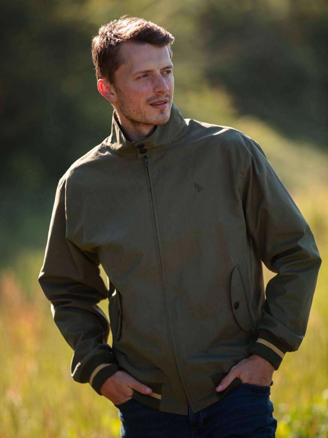Men's Harrington Jacket in olive green with zip front fastening, two front pockets, and olive check lining. Crafted in England with tonal green Partridge bird embroidery, combining timeless style, practicality, and superior craftsmanship.