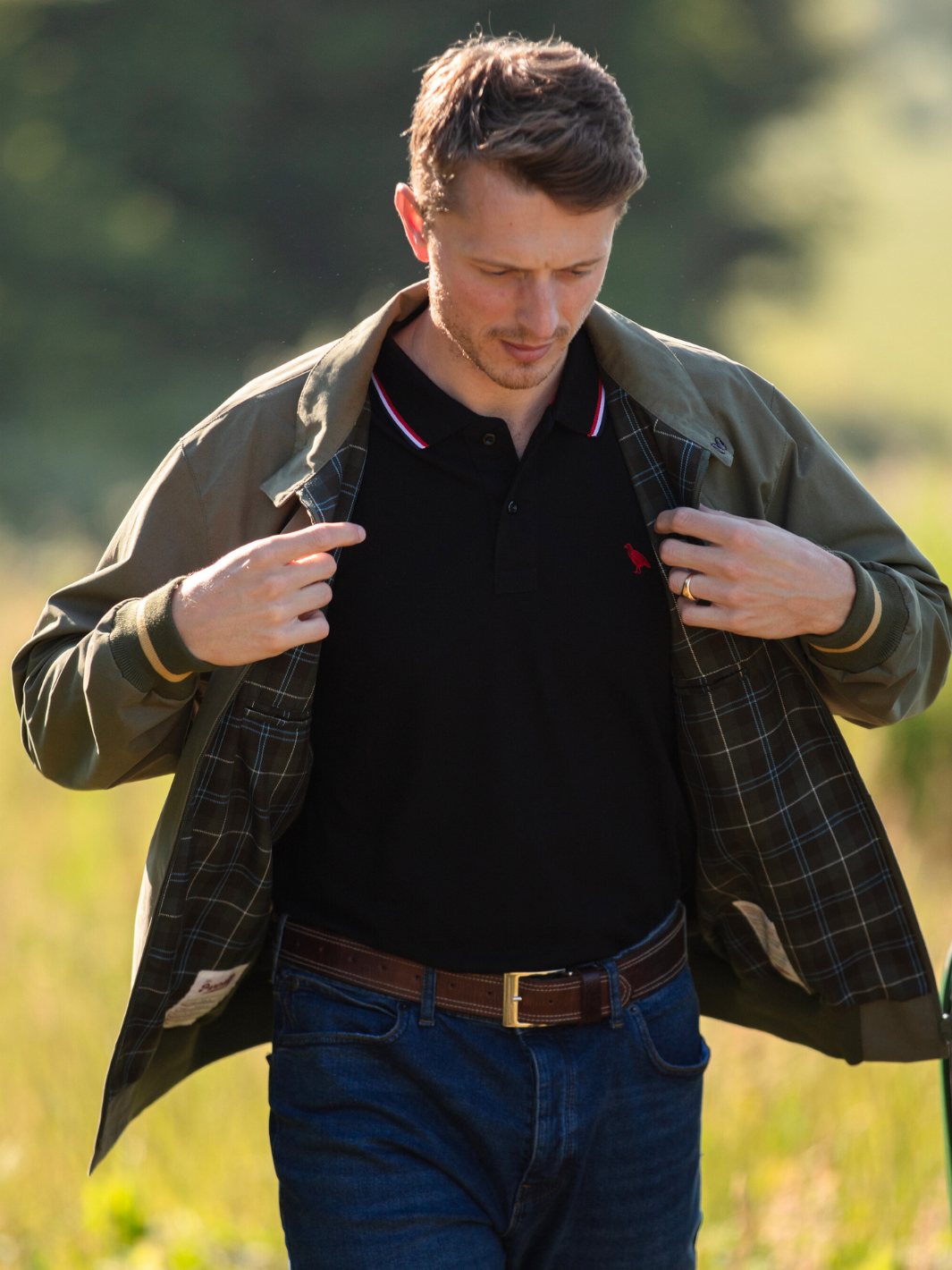 Men's Harrington Jacket in olive green with zip front fastening, two front pockets, and olive check lining. Crafted in England with tonal green Partridge bird embroidery, combining timeless style, practicality, and superior craftsmanship.