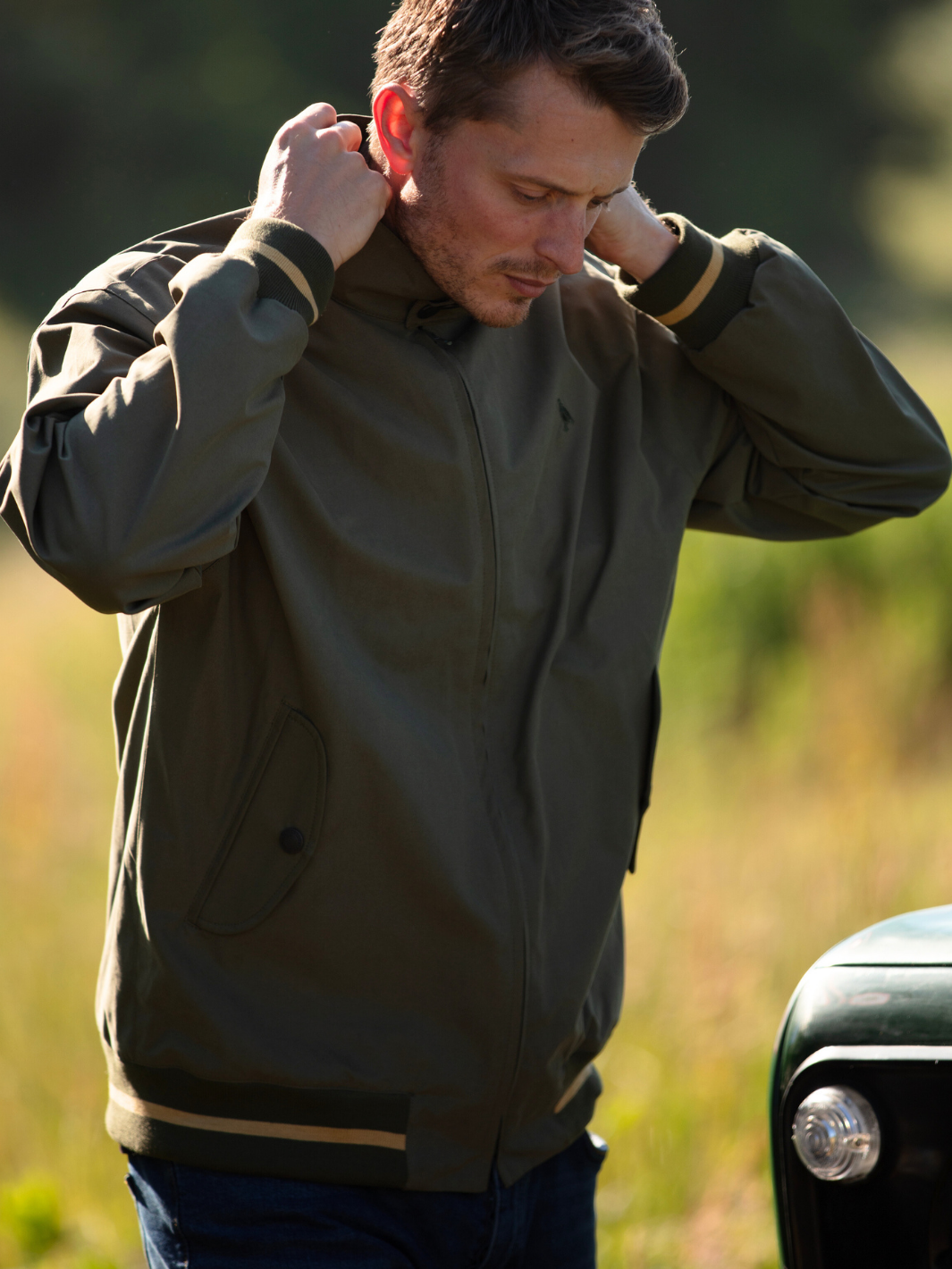 Men's Harrington Jacket in olive green with zip front fastening, two front pockets, and olive check lining. Crafted in England with tonal green Partridge bird embroidery, combining timeless style, practicality, and superior craftsmanship.