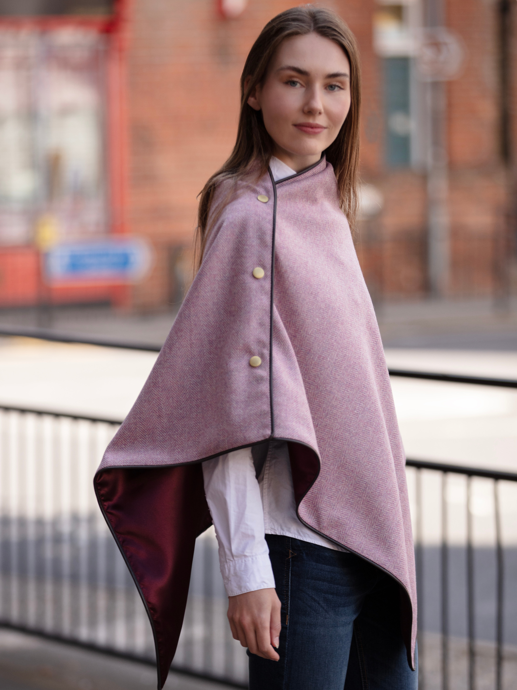 Soft pink herringbone tweed shawl with burgundy satin lining, gold studs, and dark brown faux leather trim, made in the UK by John Partridge.