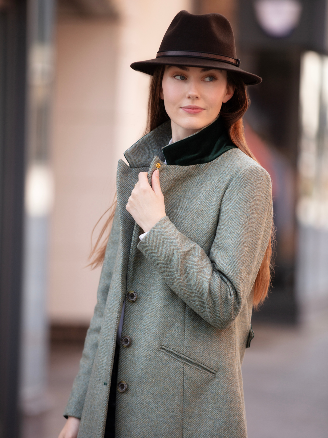 Lichfield Long Ladies' Tweed Coat in pastel green herringbone wool with John Partridge branded buttons, soft satin turquoise lining, forest green velvet cuffs and under collar, and reversible back belt. Features include 2 front pockets, back vent, and knee-length design. Available in pastel green, pink, and blue. Made in England.