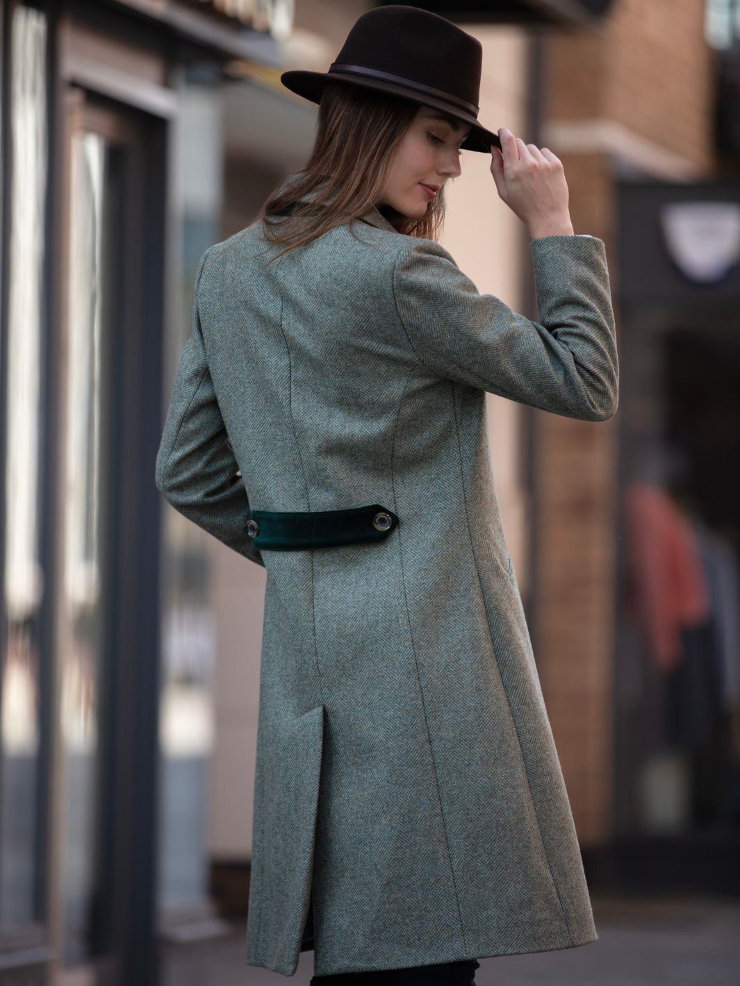 Lichfield Long Ladies' Tweed Coat in pastel green herringbone wool with John Partridge branded buttons, soft satin turquoise lining, forest green velvet cuffs and under collar, and reversible back belt. Features include 2 front pockets, back vent, and knee-length design. Available in pastel green, pink, and blue. Made in England.