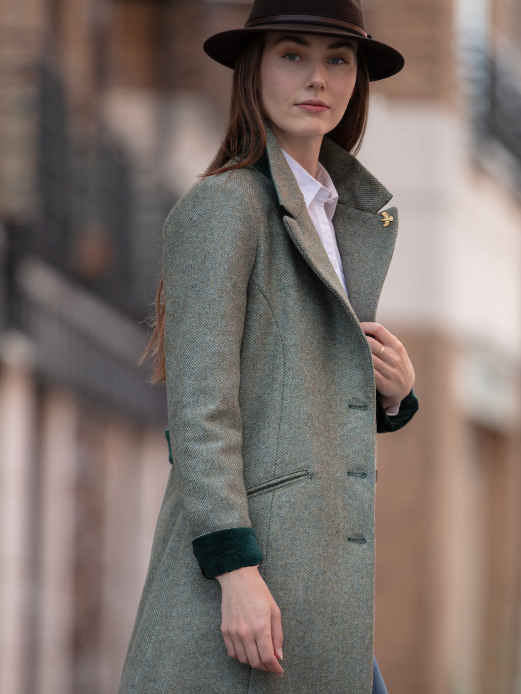Lichfield Long Ladies' Tweed Coat in pastel green herringbone wool with John Partridge branded buttons, soft satin turquoise lining, forest green velvet cuffs and under collar, and reversible back belt. Features include 2 front pockets, back vent, and knee-length design. Available in pastel green, pink, and blue. Made in England.