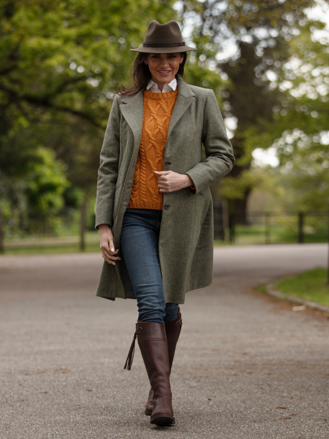 Lichfield Long Ladies' Tweed Coat in pastel green herringbone wool with John Partridge branded buttons, soft satin turquoise lining, forest green velvet cuffs and under collar, and reversible back belt. Features include 2 front pockets, back vent, and knee-length design. Available in pastel green, pink, and blue. Made in England.