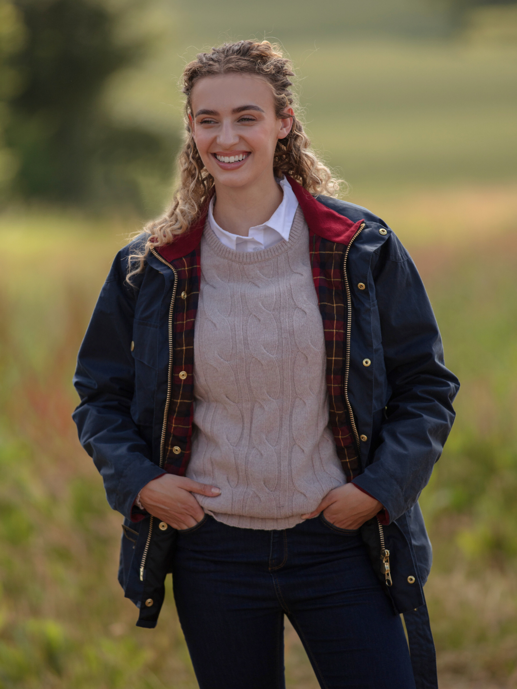 Wax Biker Jacket in Ocean Navy with cherry check lining, burgundy cotton moleskin collar, oversized pockets, and detachable belt. Crafted from British waxed material with tonal embroidery and gold-coloured studs for a blend of tradition, luxury, and modern function.