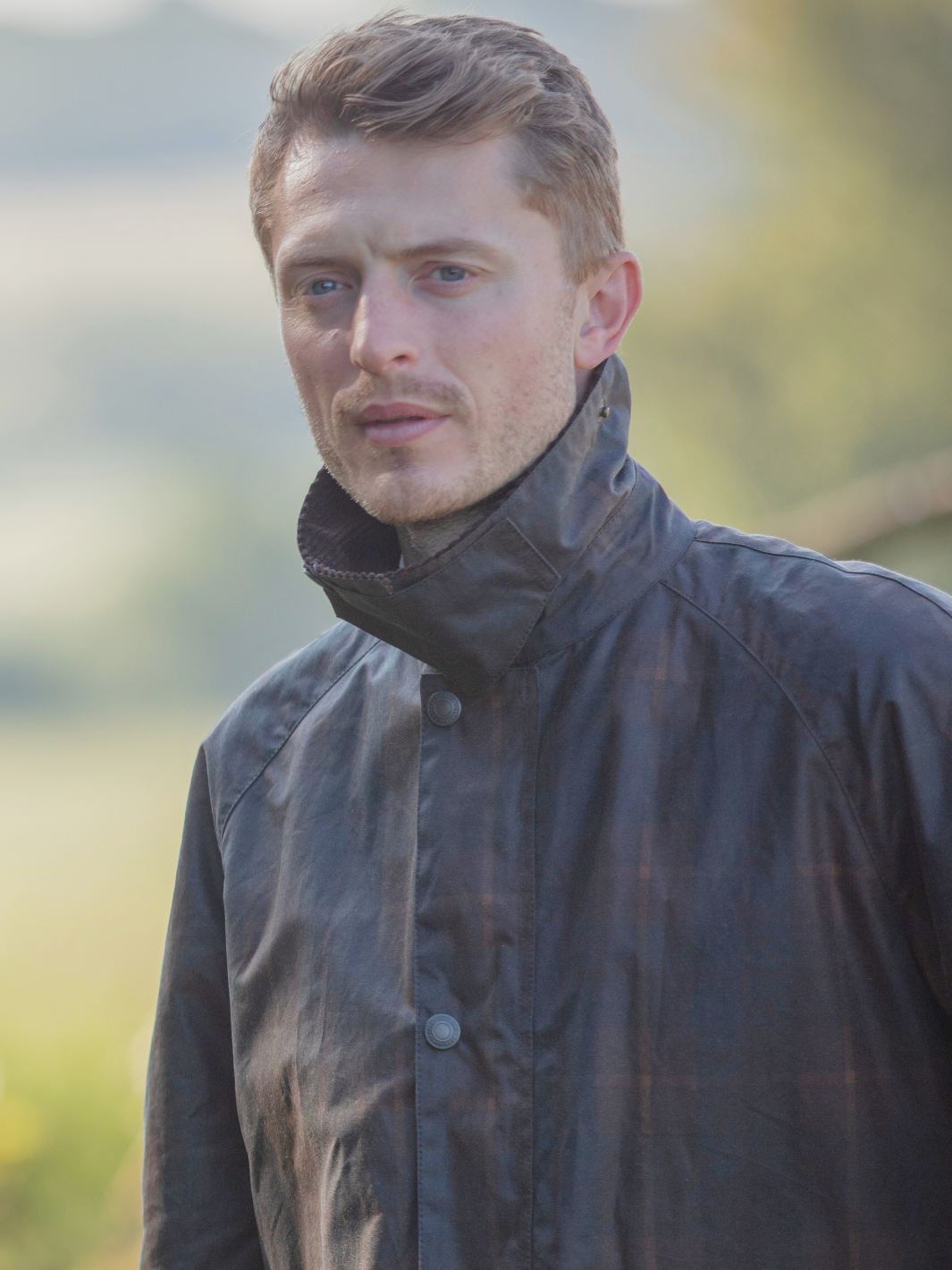 Landowner Short Wax Walking Jacket in Hunter Check with warm brown tones. A unisex, boxy-shaped waxed cotton jacket featuring cord and moleskin details for timeless elegance and weather protection, perfect for outdoor adventures or everyday wear.