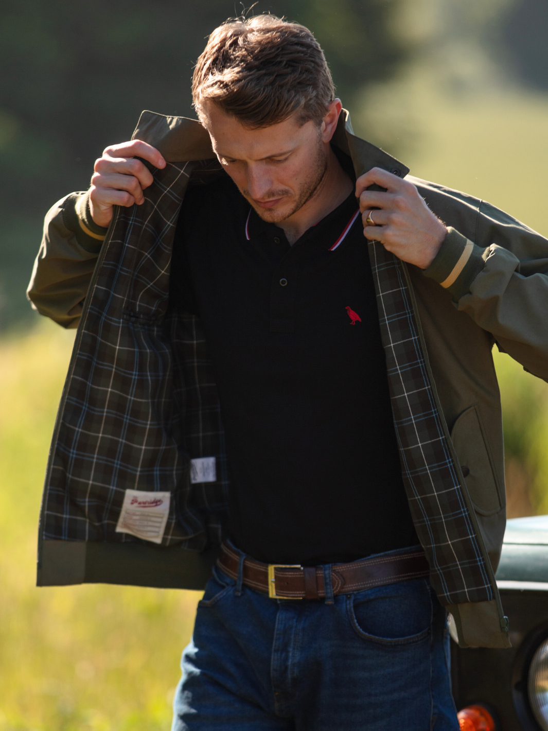 Men's Harrington Jacket in olive green with zip front fastening, two front pockets, and olive check lining. Crafted in England with tonal green Partridge bird embroidery, combining timeless style, practicality, and superior craftsmanship.