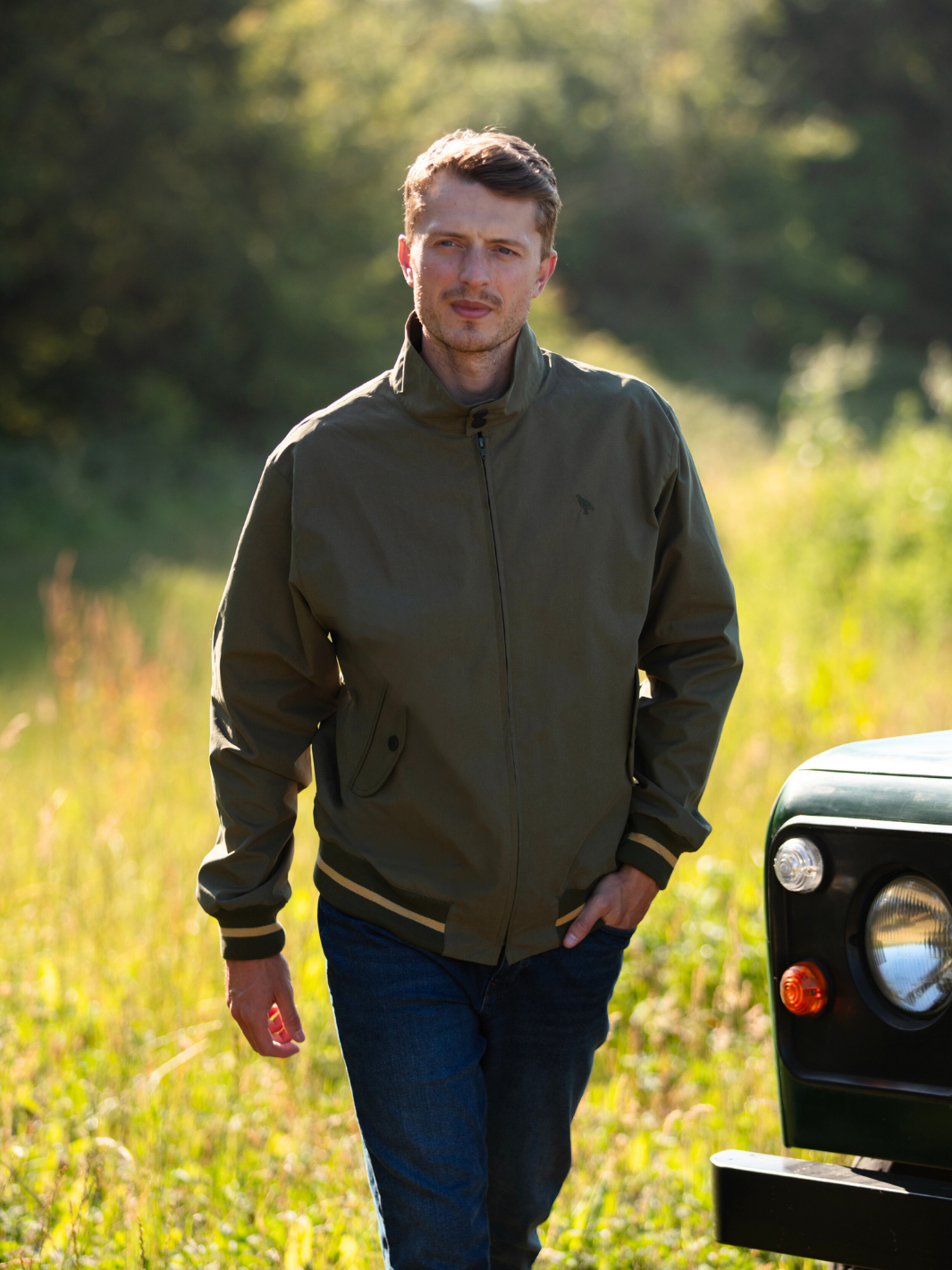Men's Harrington Jacket in olive green with zip front fastening, two front pockets, and olive check lining. Crafted in England with tonal green Partridge bird embroidery, combining timeless style, practicality, and superior craftsmanship.